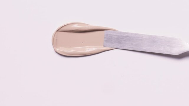 Closeup of spatula smear liquid foundation texture. Makeup composition isolated on white background. BB CC Cream Concealer swathes