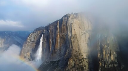 Majestic Waterfall Cascading Down Rugged Cliffs Surrounded by Soft Mist and Vibrant Rainbow in Stunning Nature Landscape Photography