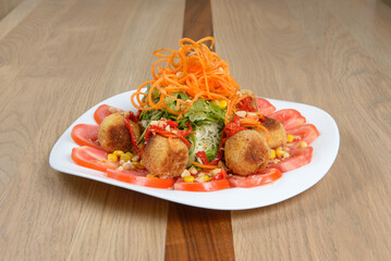 Gourmet salad with crispy spheres tomatoes corn and carrot garnish plated artfully on white dish