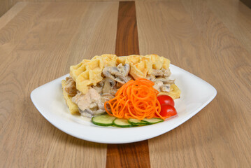 Savory waffle topped with creamy mushroom sauce shredded carrots cucumber and tomato slices