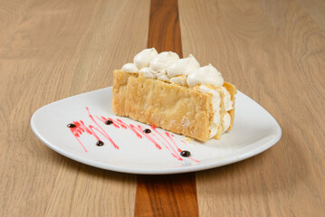 Cream filled pastry dessert is displayed on a white plate on a wooden table detailed food photography