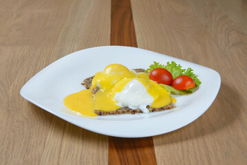 Eggs Benedict: Poached eggs on toast with hollandaise sauce served with tomatoes and lettuce