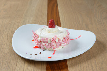Elegant dessert featuring light cream pink curls and a fresh raspberry on a white plate Yum!