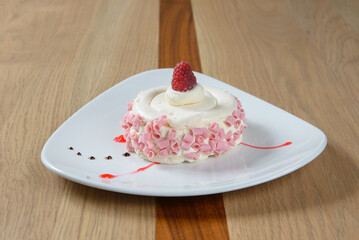 Elegant dessert on a white plate A small cake topped with a single raspberry Delicious treat