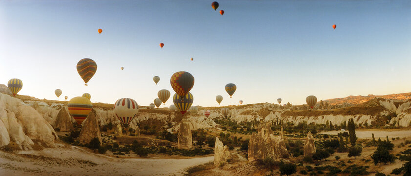 Panoramic hot air balloons over landscape at sunrise, Cappadocia, Central Anatolia Region, Turkey
