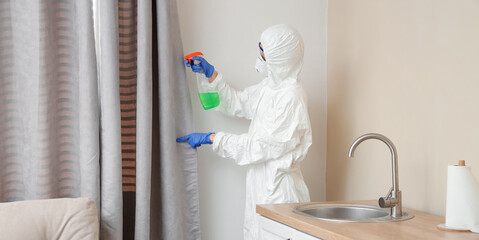 Female worker of cleaning service removing mold from curtain in kitchen