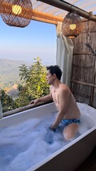 Handsome Asian Male Model Relaxing in Bathtub with Stunning Mountain View