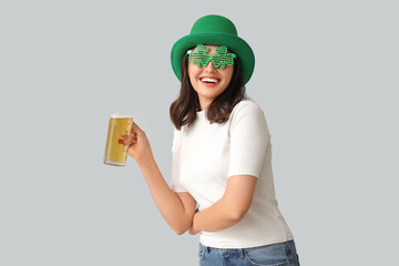 Beautiful young woman in leprechaun hat and decorative glasses in shape of clover with glass of...