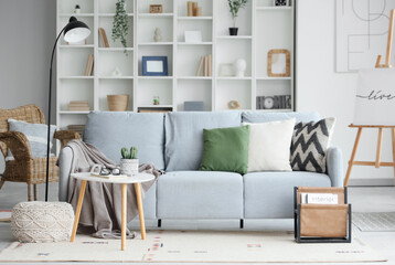 Interior of stylish modern living room with grey sofa, coffee table and shelving unit