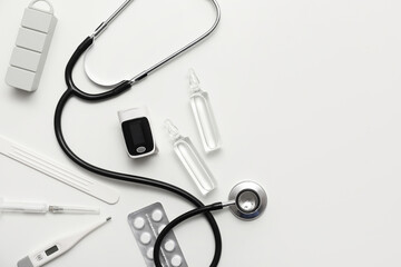 Composition with pulse oximeter, thermometer, stethoscope and medicines on white background