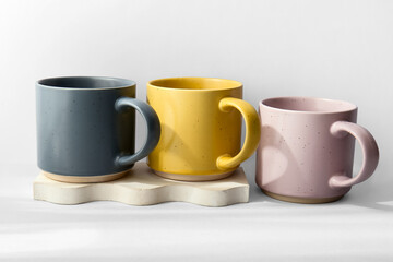 Different ceramic mugs and plaster stand on white background