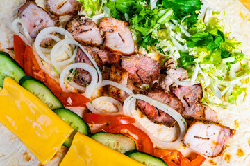 Grilled meat wrap filled with fresh vegetables and cheese