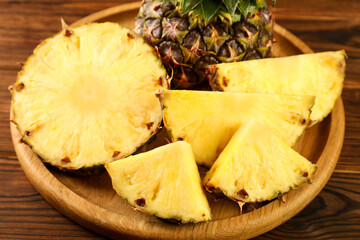 Cut fresh ripe pineapple on wooden table, closeup