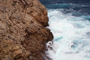 Cala Rajada coast on Mallorca island, Balearic Islands. Brown rocky cliff of blue Mediterranean Sea...