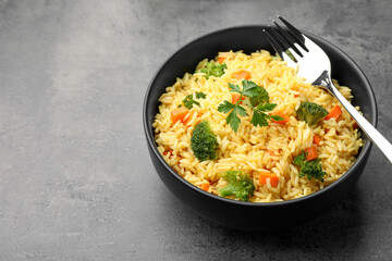 Tasty rice with vegetables on grey table, closeup. Space for text