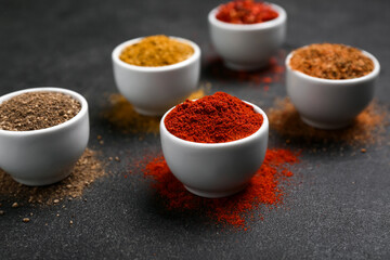 Composition with bowls of different spices on dark background
