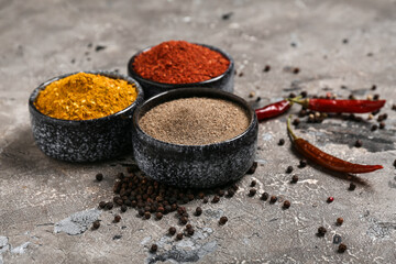 Bowls of aromatic spices, peppercorns and chili peppers on grunge background