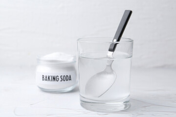 Glass of water and baking soda on white textured table, selective focus