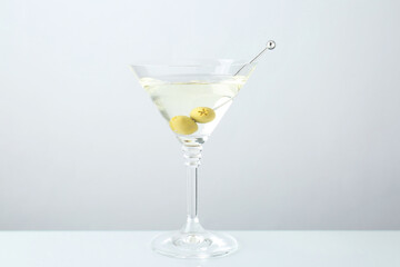 Martini cocktail with olives in glass on light grey table