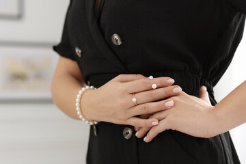 Woman wearing elegant pearl jewelry indoors, closeup