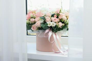 Gift box with bouquet of beautiful flowers and eucalyptus branches on window sill