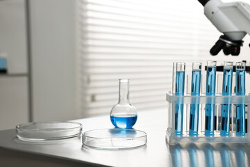 Chemical glassware and microscope on table in laboratory. Space for text