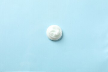 Sample of body cream on light blue background, top view