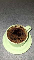 Hot Sweet Black Coffee with Thick Sediment and Strong Aroma, Served in a Ceramic Glass with a Saucer, Authentic Indonesian Coffee, Traditional Brew with Rich Foam