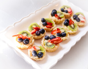 healthy dessert snack made out of fresh fruit like strawberries, blueberries, kiwi, on top of sugar cookies on a white plate