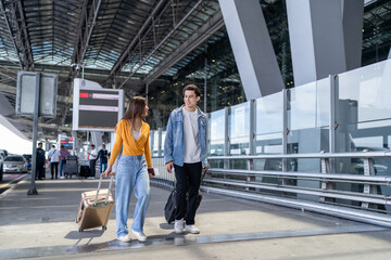 Front view of young couple walking in airport terminal to boarding gate.