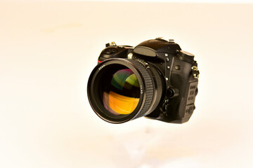 Unidentified DSLR  with 85mm prime lens on white background.