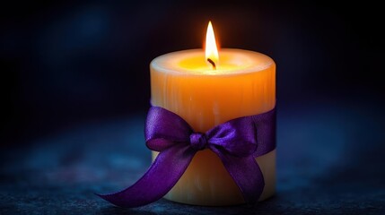 A lit candle with a purple ribbon tied around it.