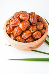 Dates fruit sukari or kurma sukari, in wooden bowl isolated on white background