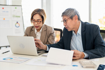 Obraz premium Man and woman are working on a presentation in meetimg room modern office. hand holding a clipboard with graphs and typing on a laptop.