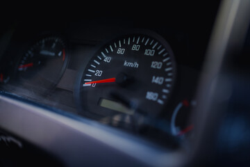 Close-up of a car speedometer illuminated in low light, showing intricate details and a modern design. Perfect for automotive themes, speed concepts, and vehicle-related content.