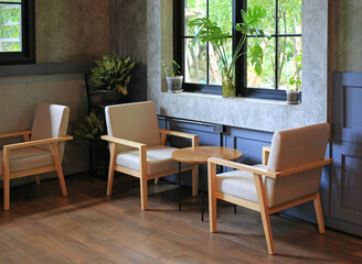 Empty round wooden table and chairs in coffee shop cafe. Seat and wood counter bar against glass window. Cafe design.
