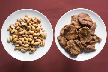 Overhead view of kuli-kuli and groundnut on a white plate, top view of nigerian groundnut cakes on a plate, fresh homemade nigerian kulikuli on a ceramic plate