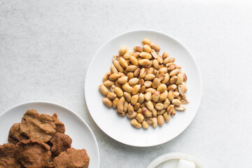 Overhead view of kuli-kuli and groundnut on a white plate, top view of nigerian groundnut cakes on a plate, fresh homemade nigerian kulikuli on a ceramic plate