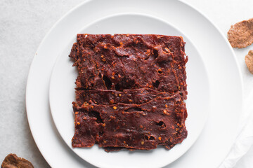 Overhead view of Nigerian kilishi on a white plate, top view of nigerian spicy beef jerky, flatlay of dried beef suya