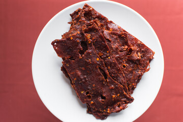 Overhead view of Nigerian kilishi on a white plate, top view of nigerian spicy beef jerky, flatlay of dried beef suya