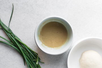 Overhead view of roux in a small bowl, top view of flour and oil mixture in a blue bowl