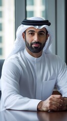 Confident Arabian businessman in white dishdasha seated at a modern office, showcasing leadership and professionalism