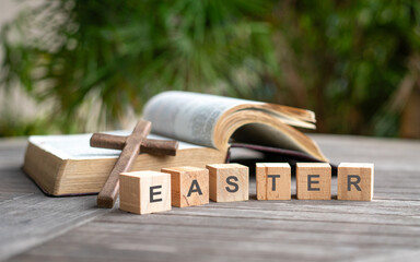 Easter, word on wooden blocks. Crucifix cross and open bible at the background. 