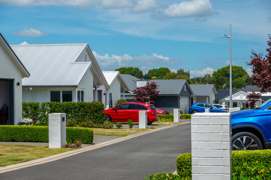 Residential street of modern low homes with red and blue cars parked in driveways