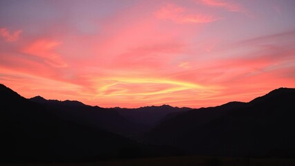 Obraz premium Majestic mountains silhouetted against a vibrant orange and pink sky at sunset, landscape, sunset, dusk
