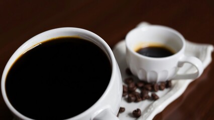 Fototapeta premium Two Cups of Black Coffee with Coffee Beans on a Wooden Table