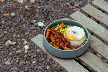 Rice Bowl dish Fried chicken, vegetables, and fried eggs on an outdoor cafe table