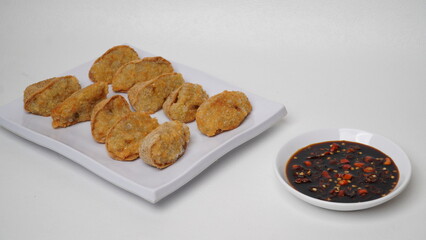 A plate of fried tofu walik served with soy sauce and chili sauce using a separate white plate placed on a white base and background (isolated white).