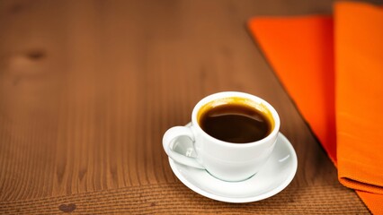 Aromatic Espresso in White Cup on Wooden Table with Orange Napkin