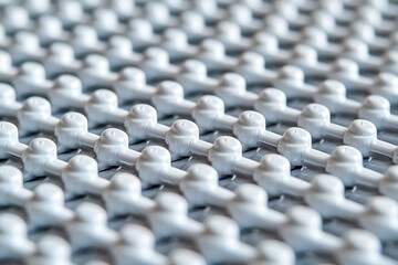 Fototapeta premium Abstract pattern of white plastic elements arranged in a grid formation creating a modern and futuristic visual texture with shallow depth of field